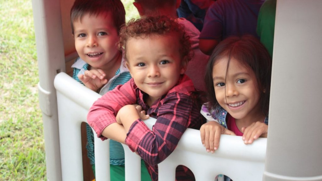 2 boys and girl sitting on white plastic chair